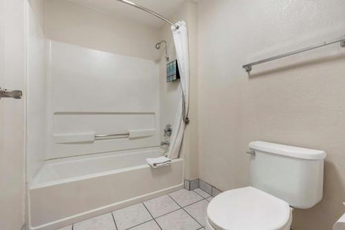 a white bathroom with a toilet and a bath tub at Best Western Colonial Inn in Selma