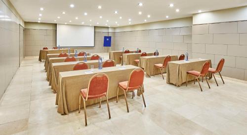 a conference room with tables and chairs and a whiteboard at NH Sport in Zaragoza