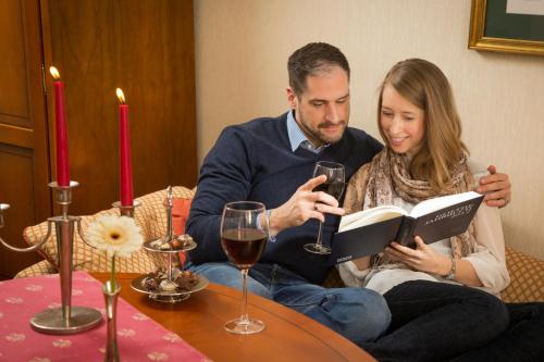 a man and woman reading a book with wine glasses at Boutique-Hotel Amalienhof in Weimar