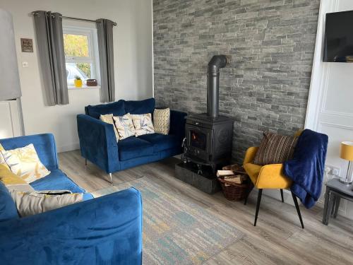 a living room with two blue couches and a wood stove at Glenhill - Newly renovated in a unique location in Belmullet