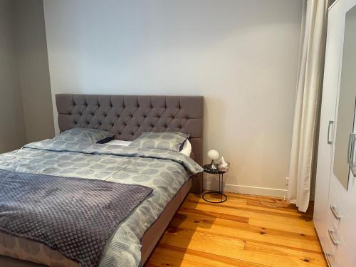 een slaapkamer met een bed en een houten vloer bij Le cocon tournaisien in Tournai