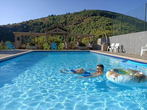 un homme se posant dans une piscine avec un ballon d'eau dans l'établissement La Vallée, à Lacrouzette