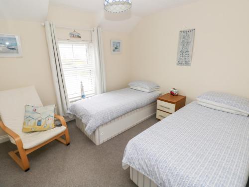 サンダースフットにあるSandyhill Houseのベッドルーム1室(ベッド2台、椅子、窓付)