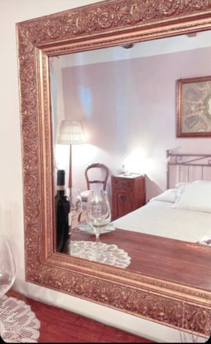 a mirror reflecting a bedroom with a bed and a wine glass at Guesthouse da Idolina dal 1946 in Montalcino