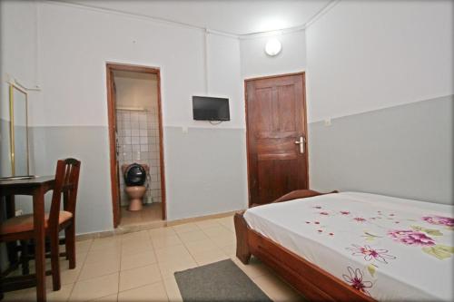 a bedroom with a bed and a table and a television at Amy's Hotel in Lomé