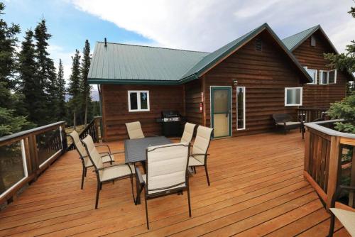 a deck with a table and chairs on a cabin at 3 Bedroom Home with Amazing Views 11 mi from Denali in Healy