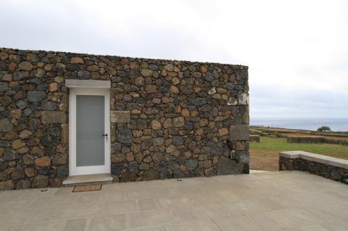 a stone wall with a white door on it at Casa Branca do Porto in Cinco Ribeiras
