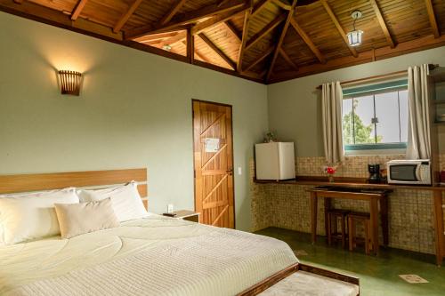 a bedroom with a bed and a kitchen with a microwave at Chalés Vale da Lua in Gonçalves