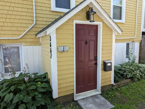 una porta rossa su una casa gialla con una cassetta della posta di Cozy 1-bedroom in Bauer Terrace next to Citadel a Halifax