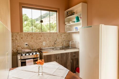 a kitchen with a table and a refrigerator at Chalés Vale da Lua in Gonçalves