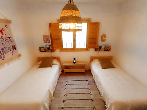 three beds in a room with a chandelier at APARTAMENTO AMANECER in Zahara de la Sierra