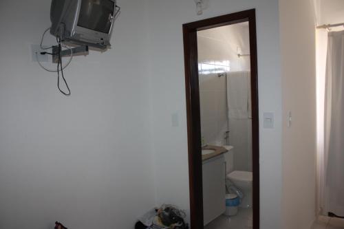 a bathroom with a toilet and a television on a wall at Paraiso Moradas in Porto Seguro