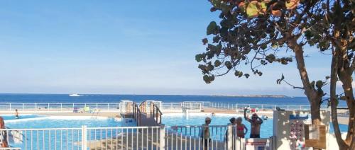 a swimming pool next to the ocean with people in it at Top floor unit 520 ft2 - 48 m2 with stunning dominant view on ocean, St Barth, Orient Bay in Cul de Sac