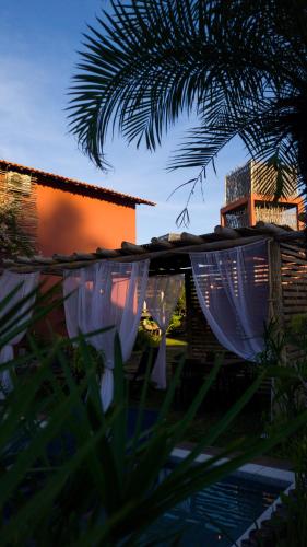 a pool of water with a house and a palm tree at Pousada Vila Camurim in Atins