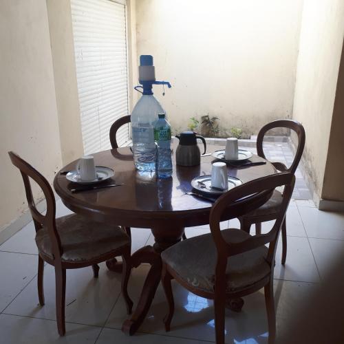 a wooden table with a bottle of water and two chairs at ZAC MBAO - Cité enseignants in Kammba