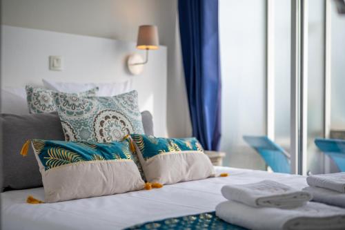 - un lit avec des oreillers bleus et blancs et une fenêtre dans l'établissement LE COQ - Splendide vue ! - Beautiful pool - FREE parking !, à Cap d'Ail