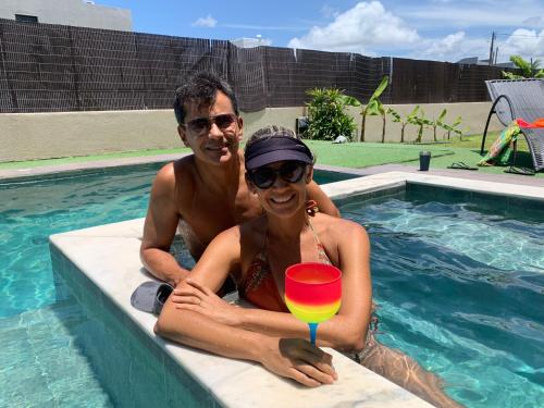 un hombre y una mujer en una piscina con una bebida en Espetacular Casa de Charme em São Miguel do Gostoso - Salou, en São Miguel do Gostoso