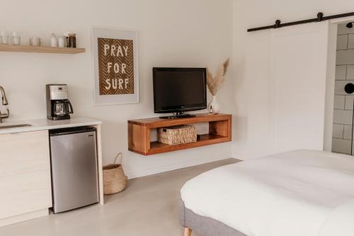 een kamer met een tv, een bed en een keuken bij Drift West Coast Getaway in Ucluelet