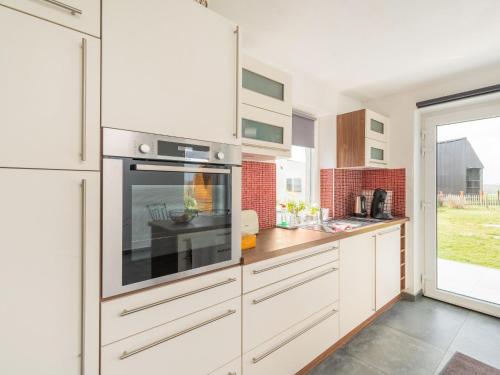 a kitchen with white cabinets and a large window at Charming Cottage with Sauna in Audregnies