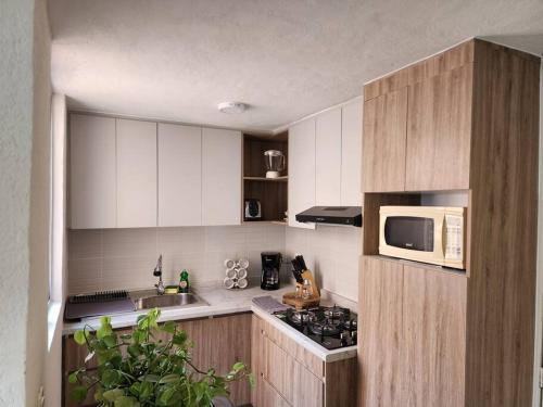 a kitchen with a microwave and a stove top oven at Práctico y cómodo caminando a la Expo Guadalajara in Guadalajara