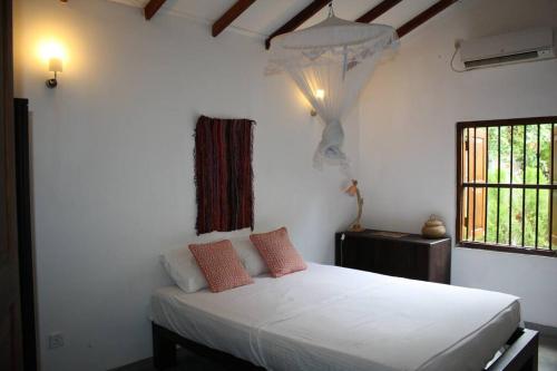 a bedroom with a white bed and a window at Casa Tangalle ~ Peaceful, private villa in Tangalle