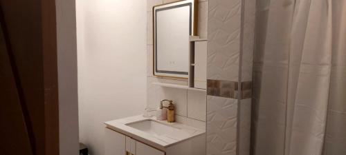 a white bathroom with a sink and a mirror at Amazing Beach View Apartments in Castries
