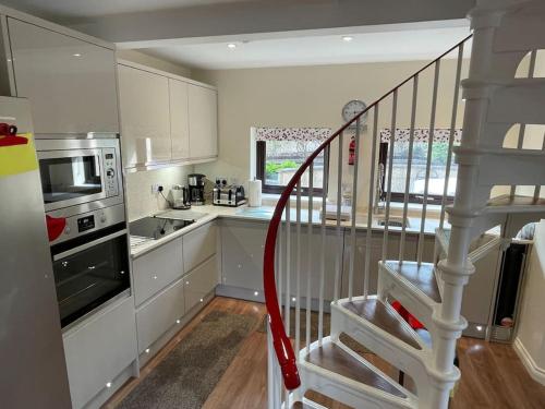 a kitchen with white cabinets and a spiral staircase at The Apartment in Nairn