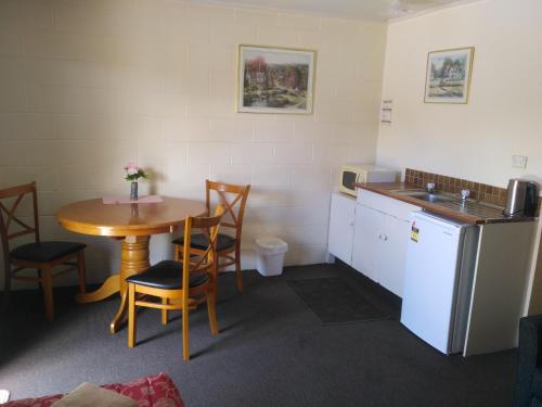 a small room with a table and a kitchen at Amble Inn Motel in Levin