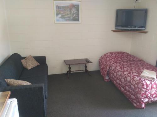 a room with a bed and a couch and a tv at Amble Inn Motel in Levin