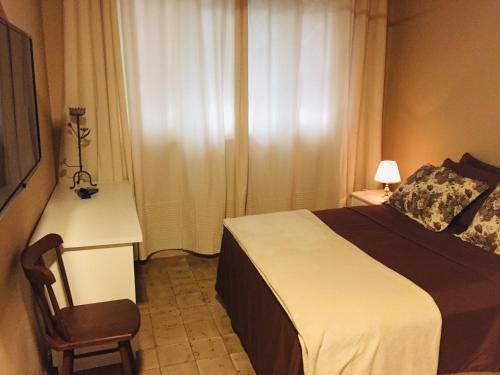 a bedroom with a bed and a desk and a chair at Pousada Familiar e Domiciliar in Lauro de Freitas
