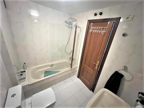 uma casa de banho com um WC, uma banheira e uma porta em playa Santa Cristina em Oleiros