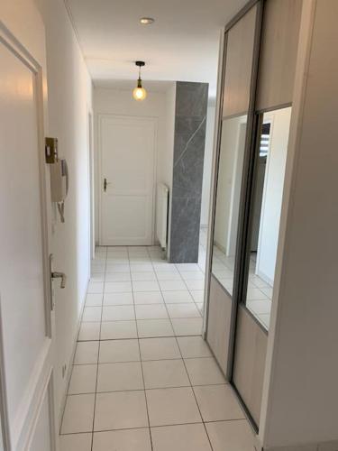 a hallway with a white tiled floor and a white door at Appartement Premium Le Marquis in Pfastatt