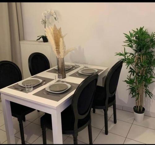 a white table with chairs and plates and flowers on it at Appartement Premium Le Marquis in Pfastatt