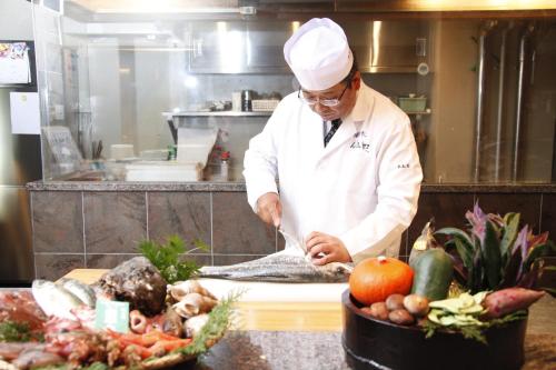 a chef preparing a fish in a kitchen at Rurikoh in Kaga