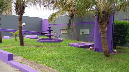 a purple building with palm trees and a fountain at Motel Tropical in Ribeirão Preto