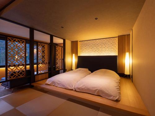 a bedroom with a bed with white sheets and lights at Sanrakuen in Tonami