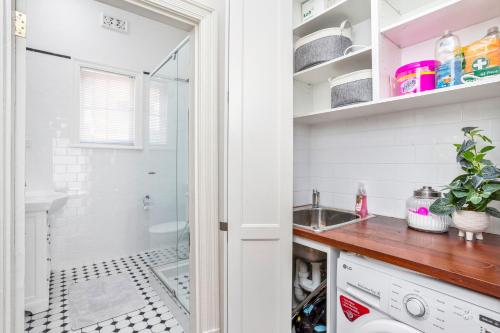 - une buanderie avec un lavabo et une douche dans l'établissement Hyde Park Vista Spacious 3br Home, à Perth