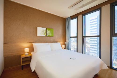 a bedroom with a large white bed and large windows at Hotel POCO Seongsu in Seoul
