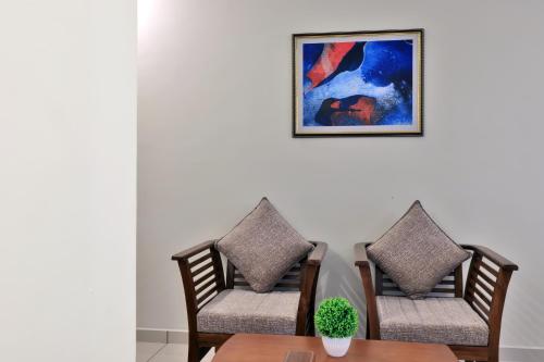 two chairs and a table with a picture on the wall at Castle Brook Residential Homestay in Thiruvalla