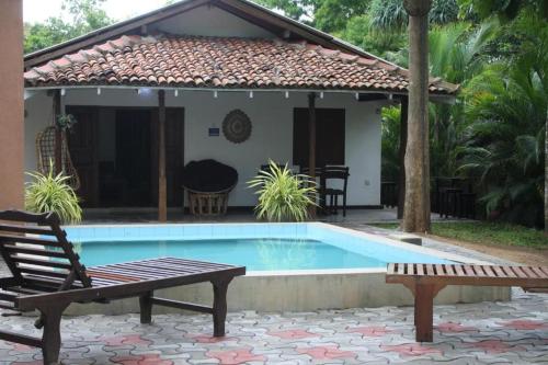 a villa with a swimming pool in front of a house at Casa Tangalle ~ Peaceful, private villa in Tangalle