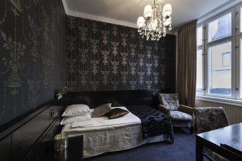 a bedroom with a bed and a chair and a chandelier at Stadshotellet Lidköping in Lidköping