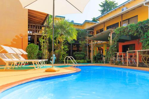 a swimming pool in front of a hotel with an umbrella at Hotel Boutique La Casa de las Flores in Cahuita