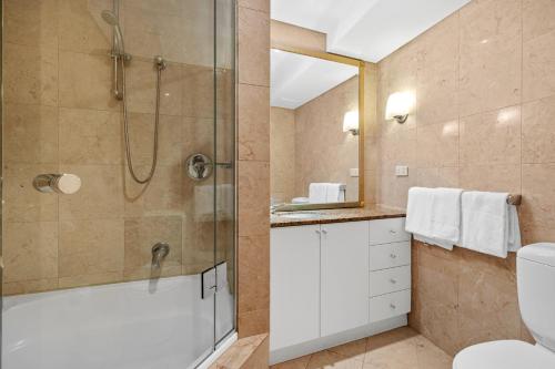 a bathroom with a shower and a toilet and a sink at Bond 1218 Self Catering in Sydney