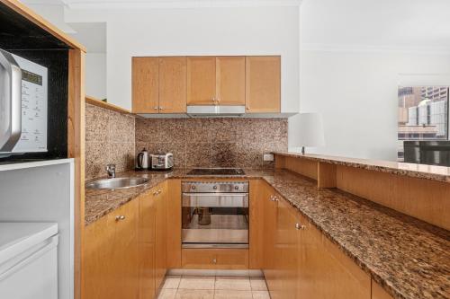 uma cozinha com armários de madeira e um lavatório em Bond 1218 Self Catering em Sydney