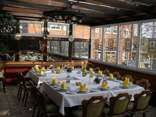 a dining room with a table and chairs and windows at Alter Dorfkrug Am Kanal in Wolfsburg