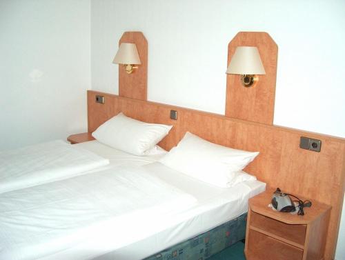 two beds in a room with two lamps on the wall at Alter Dorfkrug Am Kanal in Wolfsburg
