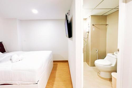 a bedroom with a white bed and a toilet at PT Grand Hotel in Ban Tha Makham