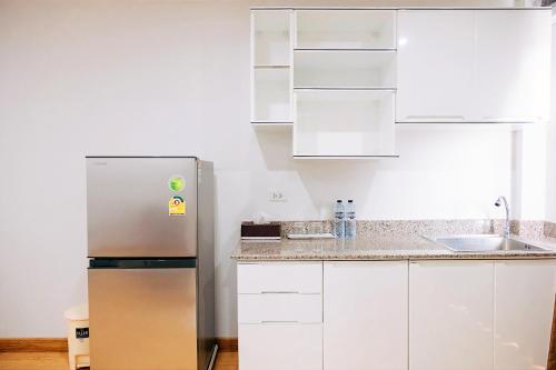 a kitchen with a stainless steel refrigerator and white cabinets at PT Grand Hotel in Ban Tha Makham