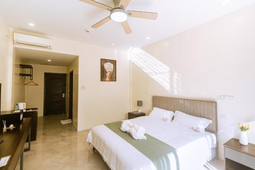 a bedroom with a white bed with a ceiling fan at Bohol Cattleya Resort in Panglao Island