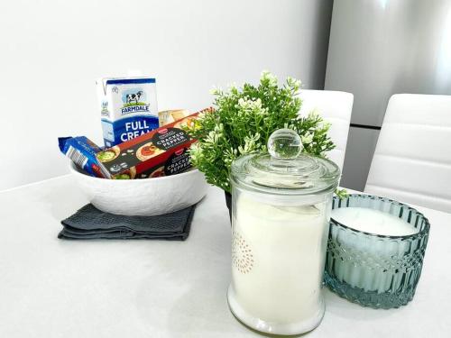 a table with a jar of milk and a bowl of food at Lovely Hidden Gem in Redcliffe in Redcliffe